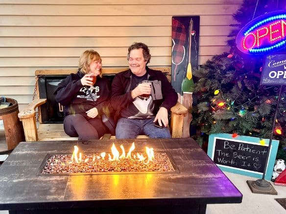  Couple sitting in front of fire drinking beer