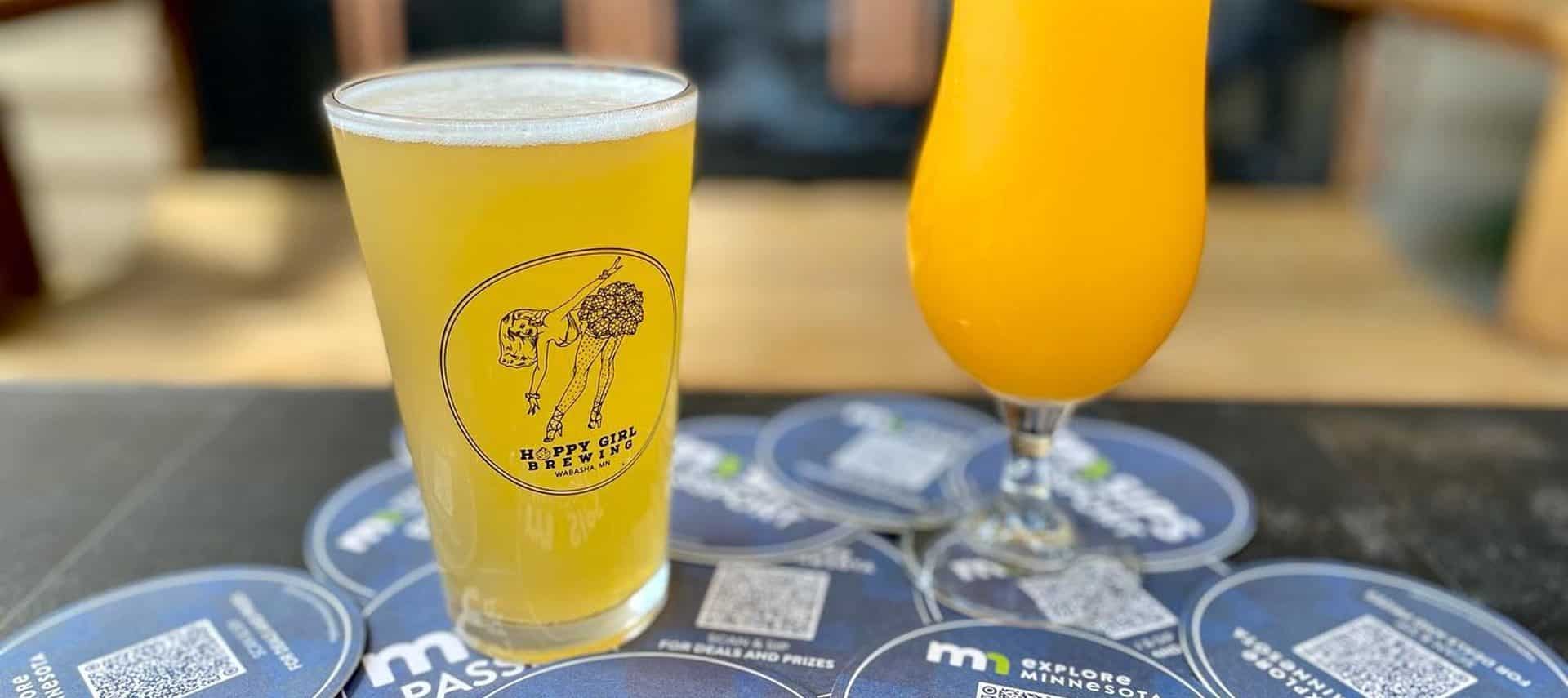 Two glasses of light yellow beer on a table with blue paper circles