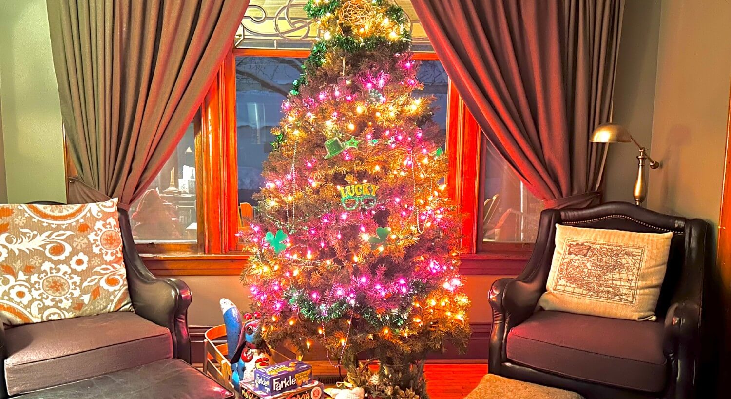 Living room of a home with a Christmas tree and gifts between two black leather chairs