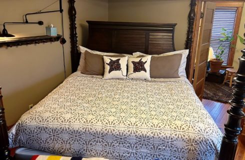 Bedroom with four poster king bed and doorway into a bathroomo