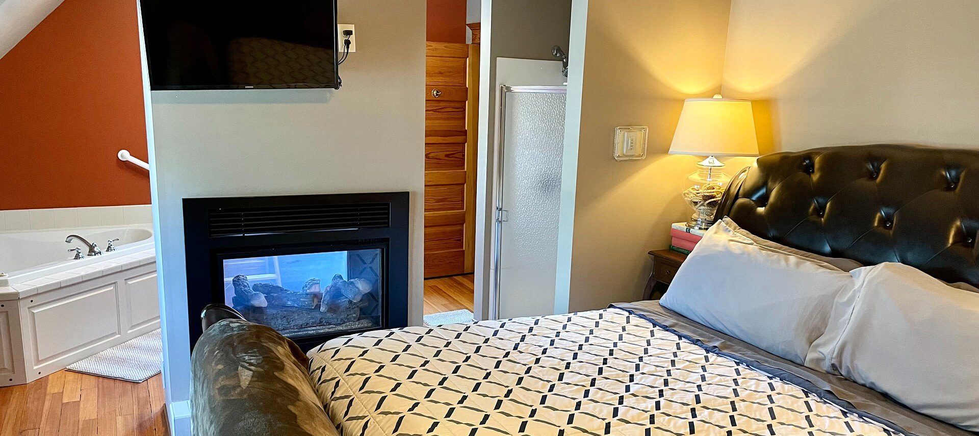 Bedroom with king bed, gas fireplace that is seen from both sides of the room and corner tub