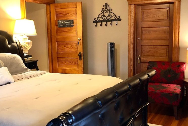 Cozy bedroom featuring king bed with black leather headboard and footboard and two red and black sitting chairs