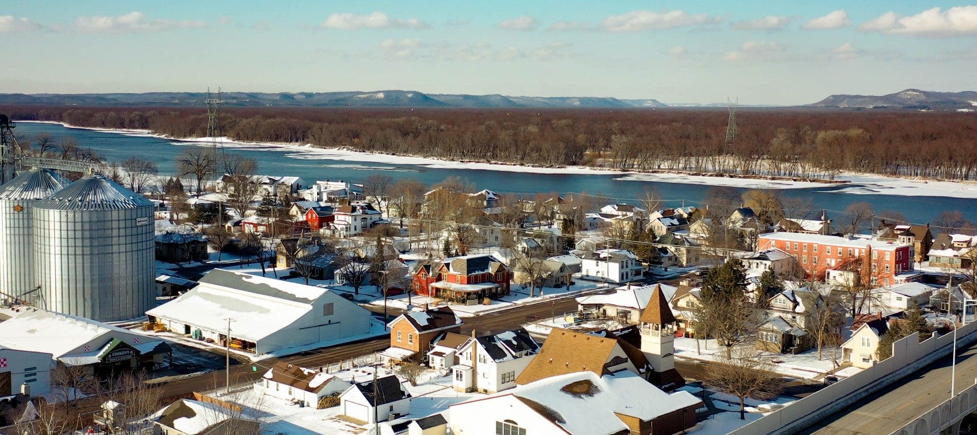 Overhead drone image above a small town dusted in snow near a large river