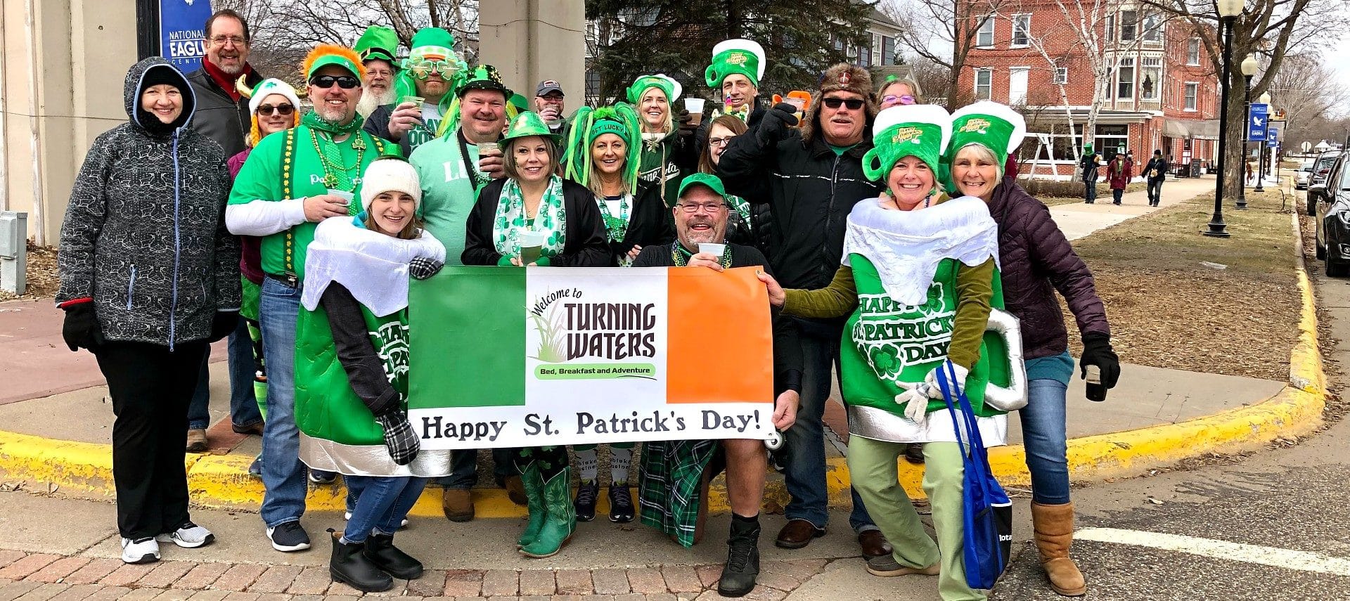A group of people dressed in green for a St. Patrick's Day parade holding a sign