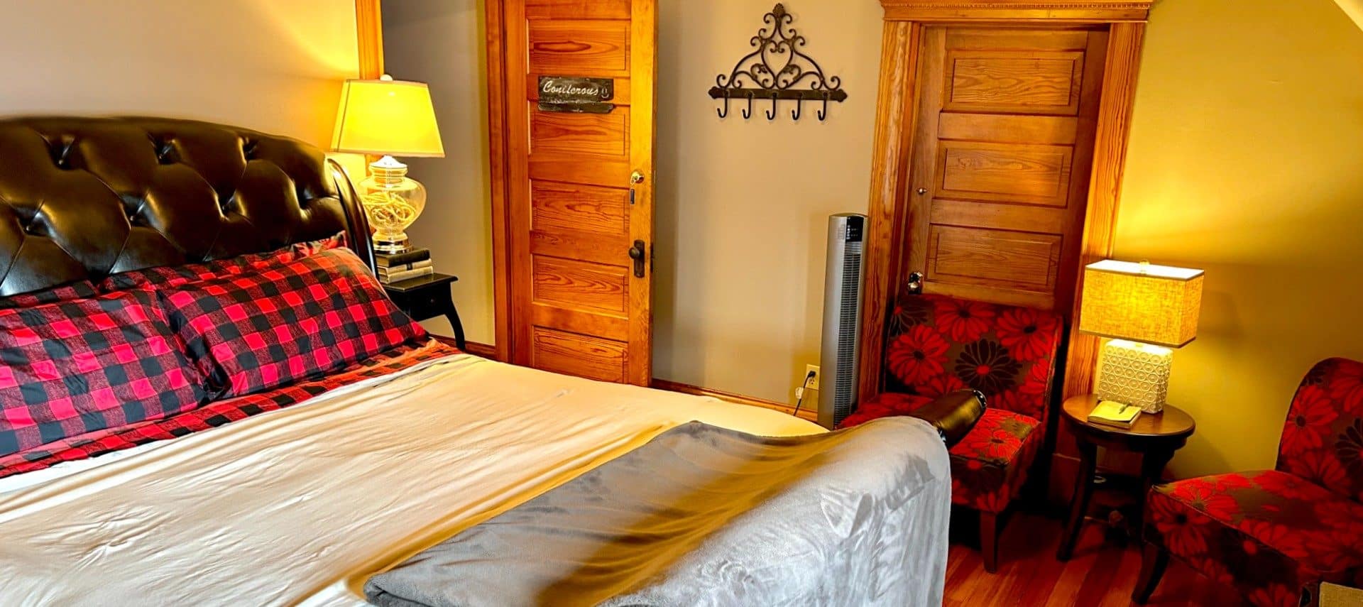 Cozy bedroom featuring king bed with black leather headboard and footboard and two red and black sitting chairs