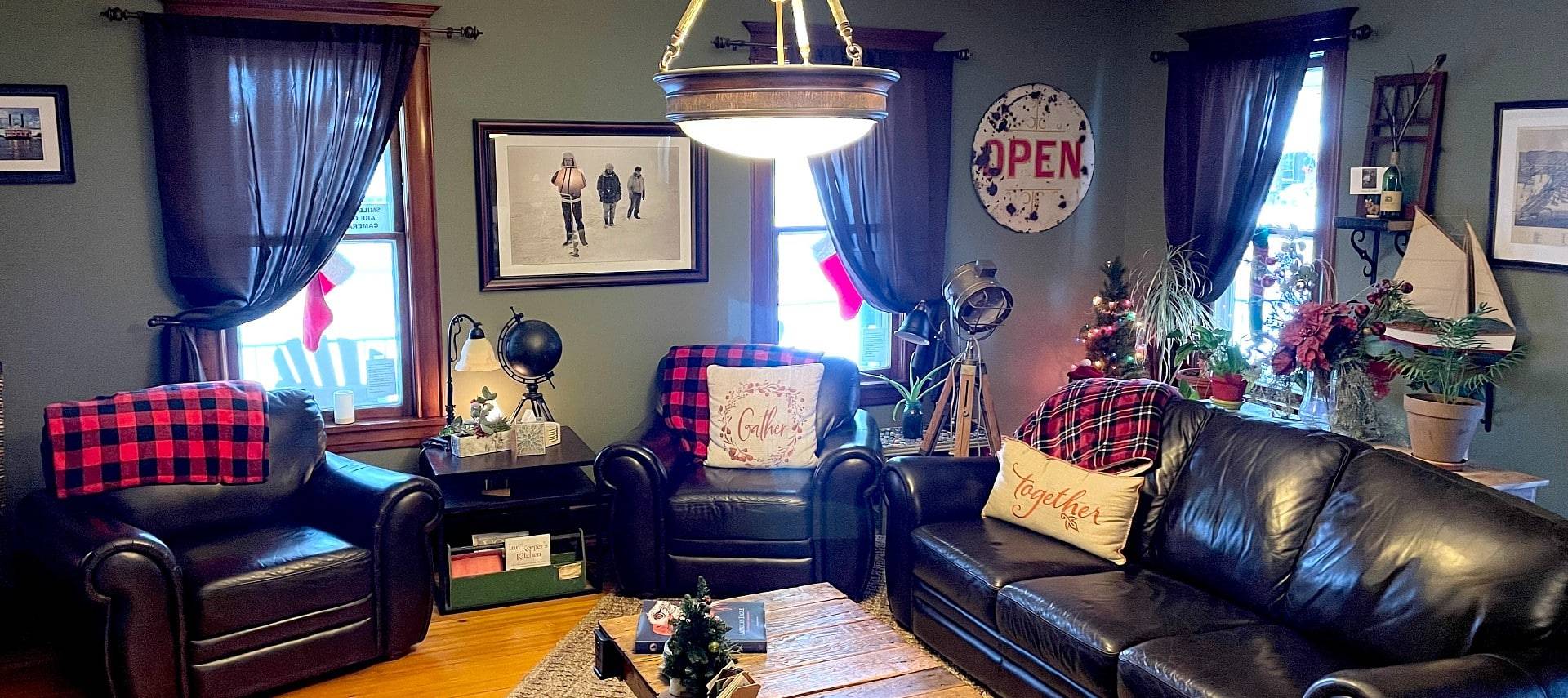Living area of a home with two black leather chairs, a leather couch and red and black decor