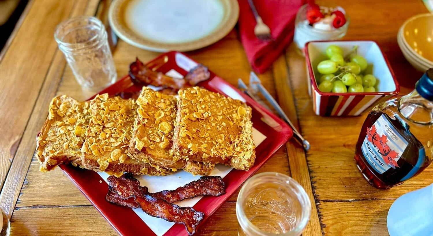 Wood dining table with breakfast food; French toast, grapes, yogurt and maple syrup