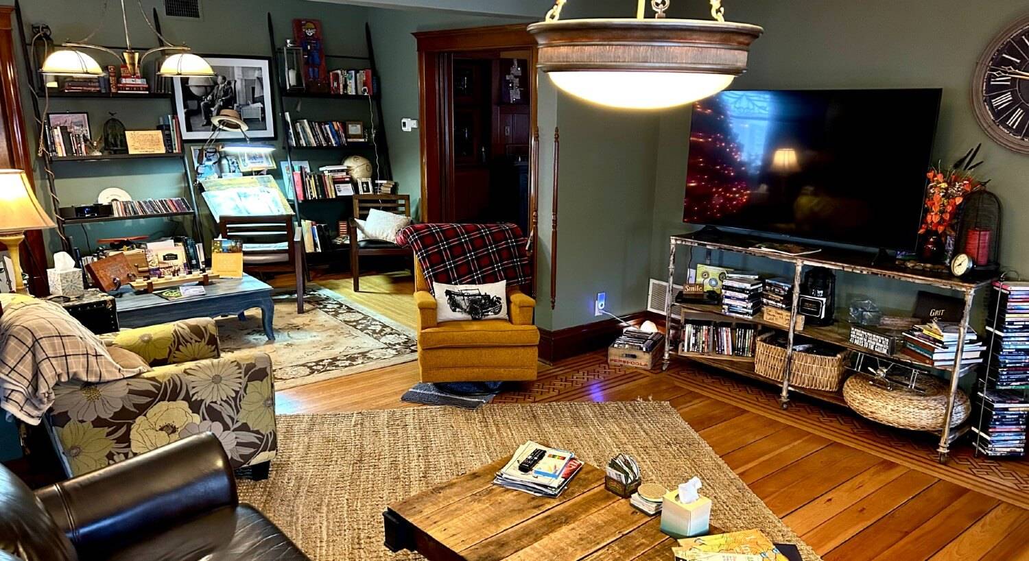 Living room of a home with TV on a console filled with books, coffee table, sitting chairs and large bookshelves